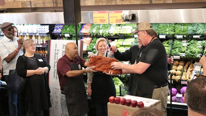 David Maloo (Assistant Store Director), Trish and Bo Sharon (owners), and Bob Knaus  (Store Director) cut house-cured bacon instead of a ribbon to celebrate the opening of Lucky’s Market