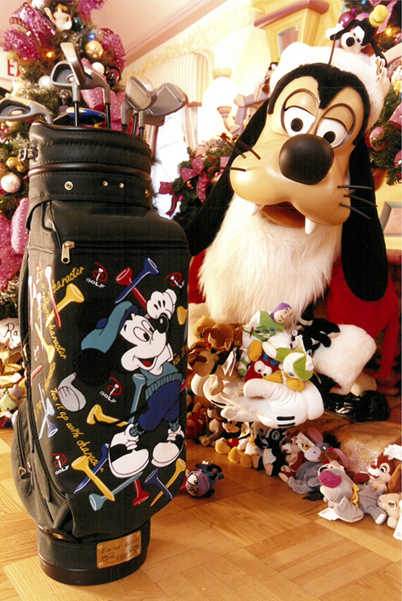 Goofy poses next to a bag of branded gifts, like this golf club set. 1998.