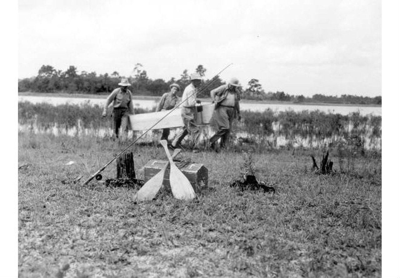 Four fishermen carry their boat from lake