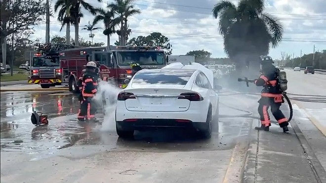 Firefighters attempt to put out flames on an electric vehicle caught from floods by Hurricane Ian