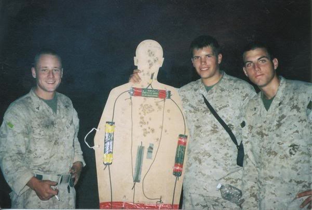 Left to Right- Lcpl. Chris Sipe, Lcpl. Mike Seimbruzch and Lcpl. Fred Lambert. 
The body-shaped target with C4 explosives strapped on was a tool the Marines used to breach heavy and locked doors in Fallujah homes.