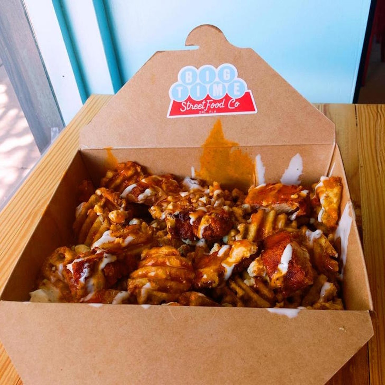 Big Time Street Food Co.: Buffalo Bird Fries  
805 E. Washington St., 407-801-5464
This is a big box of seasoned waffle fries smothered in blue cheese, topped with chunks of fried chicken, and finished with buffalo sauce and ranch. Get down on it.
Photo via Facebook/Big Time Street Food Co.