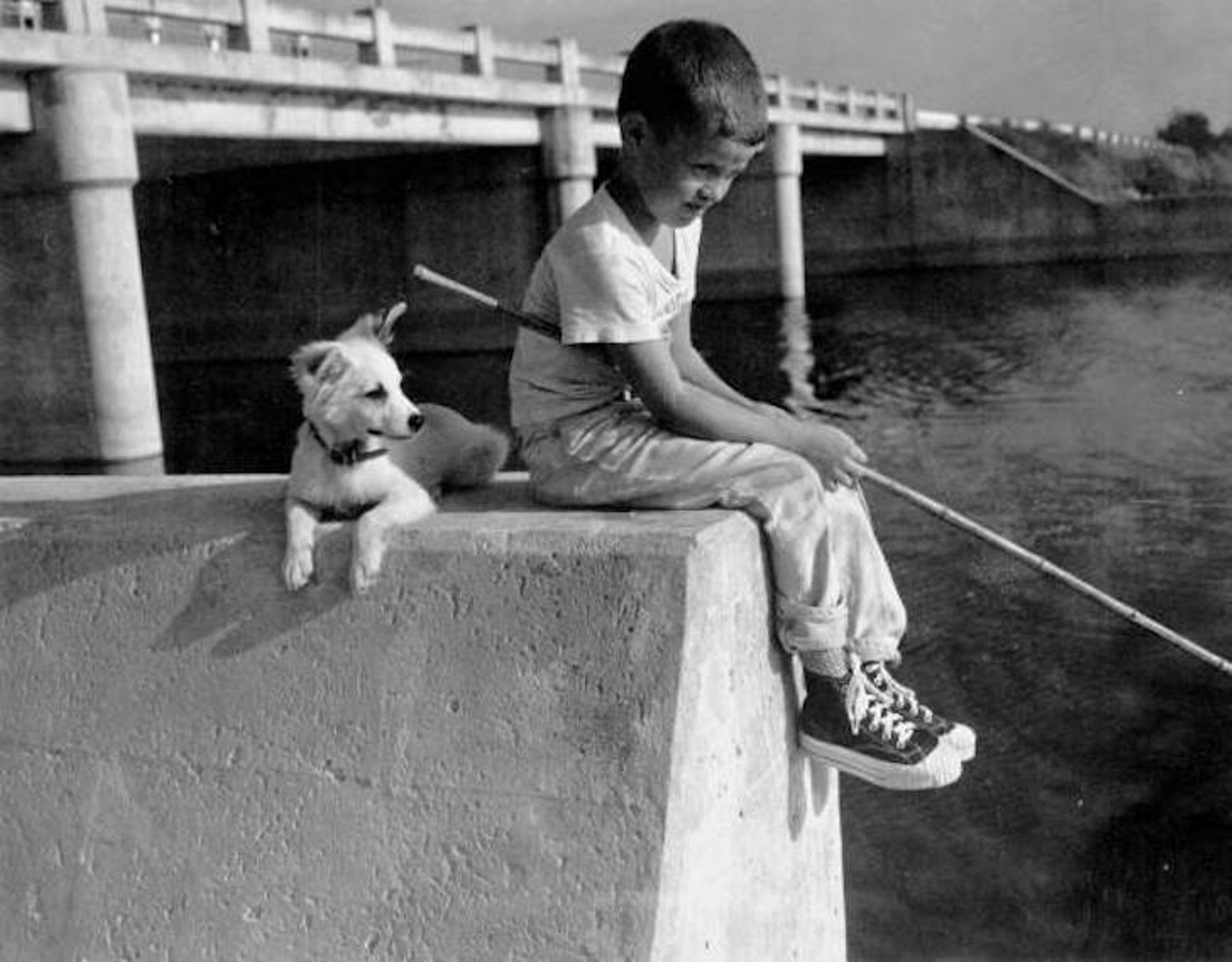 A young boy fishing with his dog in Palm Beach County, Florida, taken sometime in the 1900s.