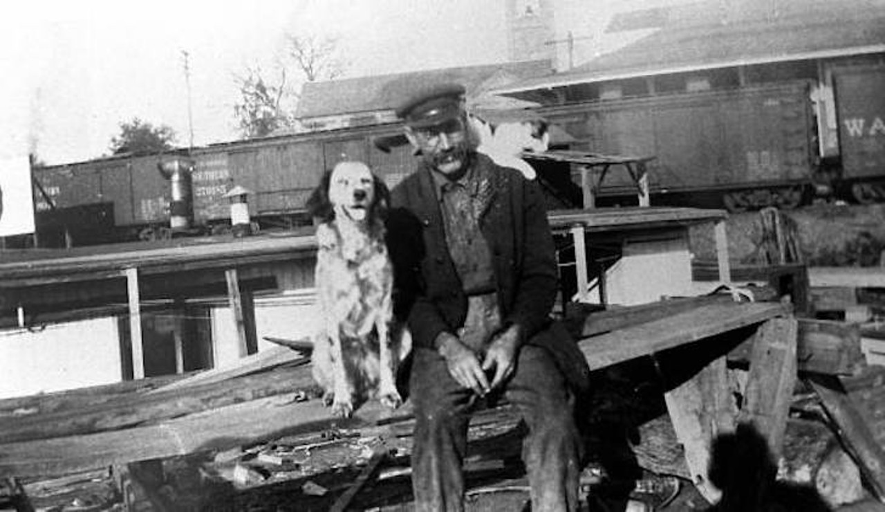 Captain Will Newman sitting on the dock with dog and cat in Palatka, Florida, taken sometime in the 1920s.
