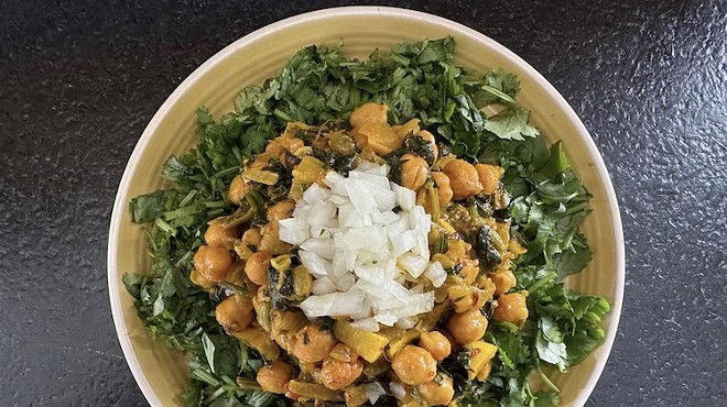 A vegetarian dish of chickpeas and spinach in a yellow bowl.