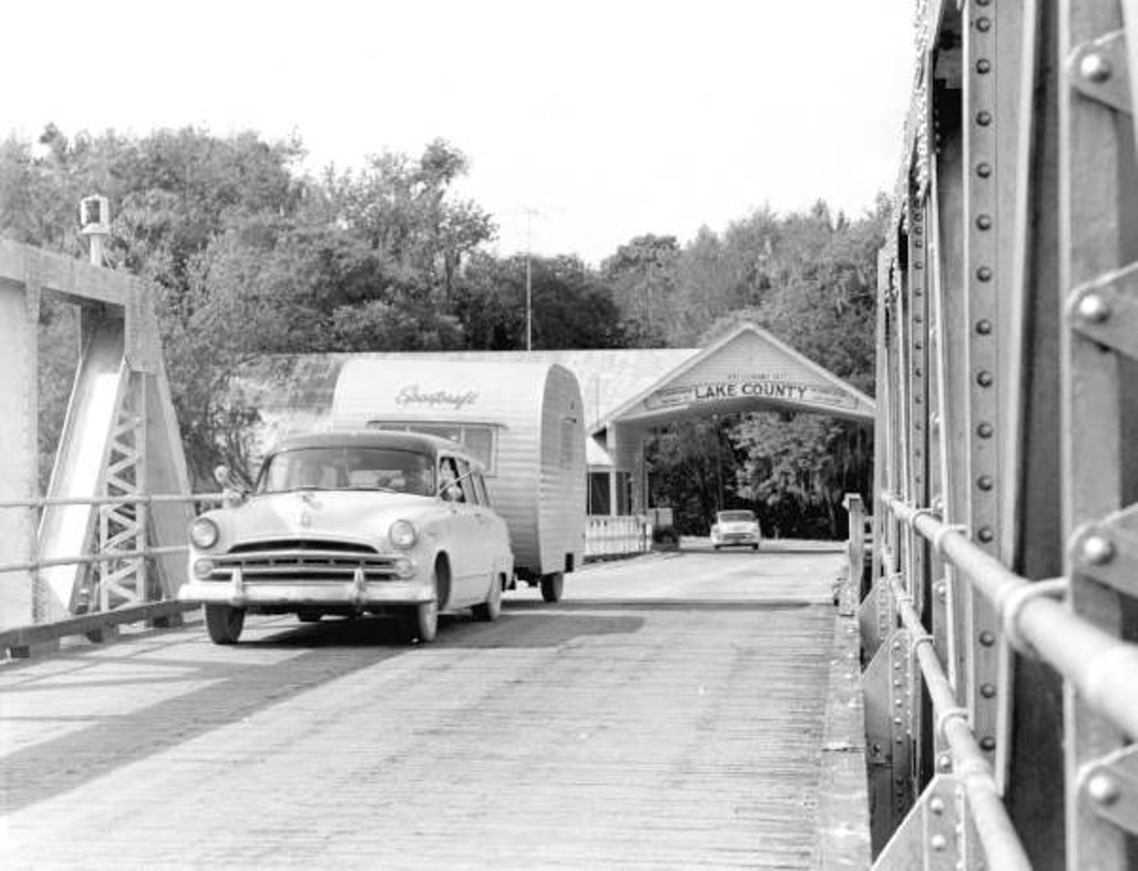 Car and trailer crossing a bridge in Astor, 1957