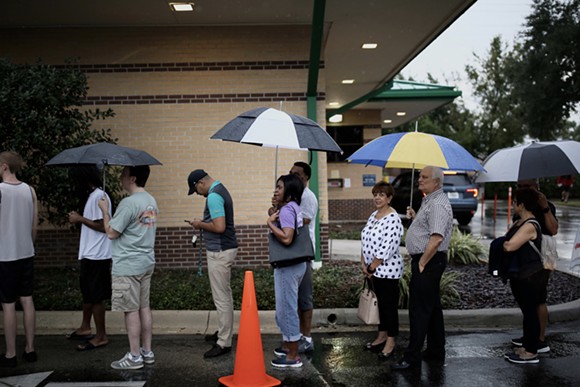Voters stand in the rain in line to vote at the Alafaya Branch Library precinct on Nov. 6 2018, the highest general election day turnout since 2012. - PHOTO BY JOEY ROULETTE