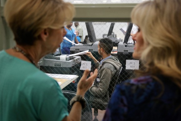 Onlookers watch rows of poll staffers tackle the first wave of recount ballots inside an Orange County Supervisor of Elections warehouse on Nov. 12 2018. - Photo by Joey Roulette