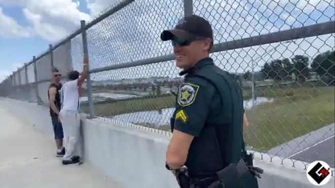 An Orange County Sheriff's Office deputy smiles while handing water to neo-Nazis. - SCREENSHOT VIA TWITTER/ST PETE COP WATCH