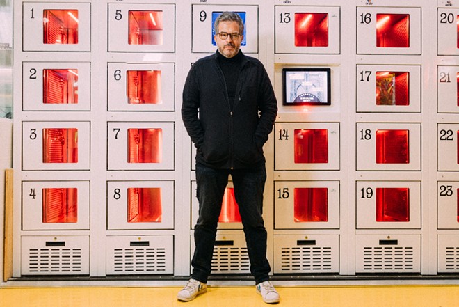 Founder Stratis Morfogen in front of a wall of heated lockers at Brooklyn Dumpling Shop. - Photo courtesy of Brooklyn Dumpling Shop