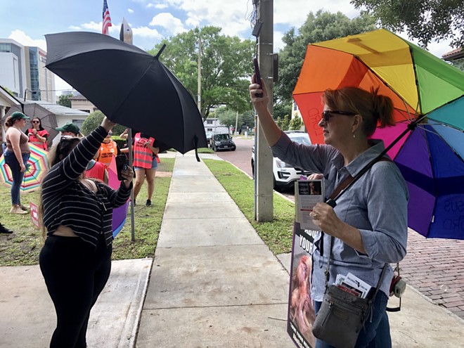 A clinic escort (left) blocks an anti-abortion protestor (right) from filming a patient walking toward an Orlando abortion clinic. April 15, 2023. - McKenna Schueler