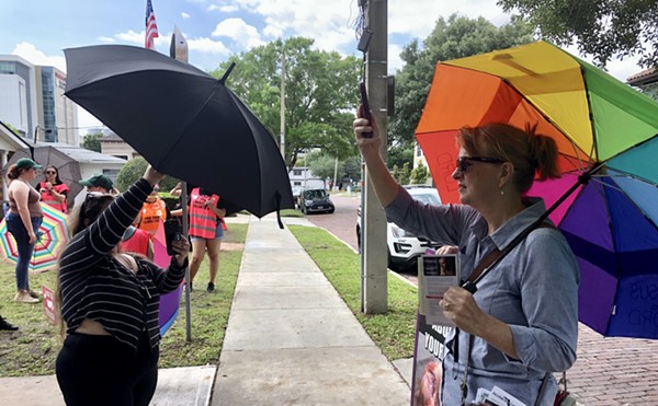 A clinic escort (left) blocks anti-abortion activist Anne Marchetti from filming a patient walking toward an Orlando abortion clinic. April 15, 2023.