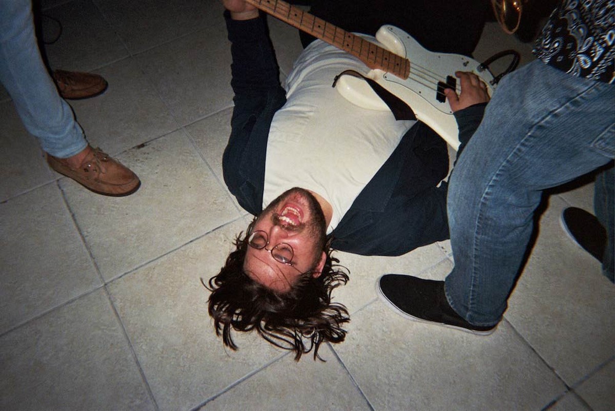 Milovac lying on the floor playing bass with Bongus