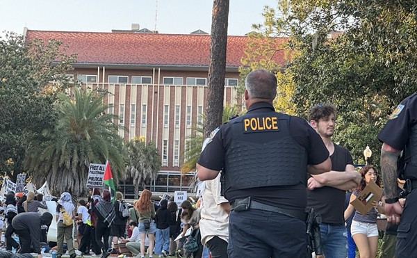 An unidentified University of Florida campus police officer watches over about 50 pro-Palestinian protesters who demonstrated on campus Thursday, April 25, 2024, for a second consecutive day. There was no violence or police response – a contrast to what was happening at some other college campuses around the U.S.