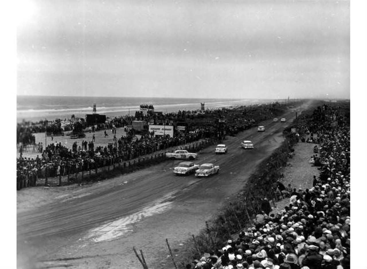 Crowds watch cars racing on the beach road